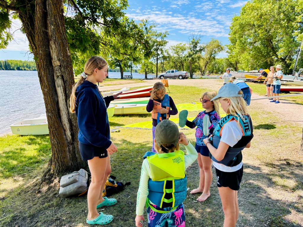 Female sailing coach teaches a group of girls on a beach